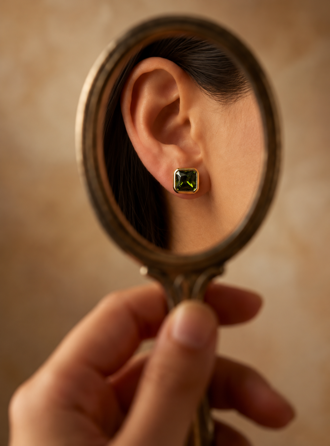 Model wearing the Alison Mariot VERDÉA earrings in 18K gold vermeil with natural green tourmaline, reflected in a hand mirror
